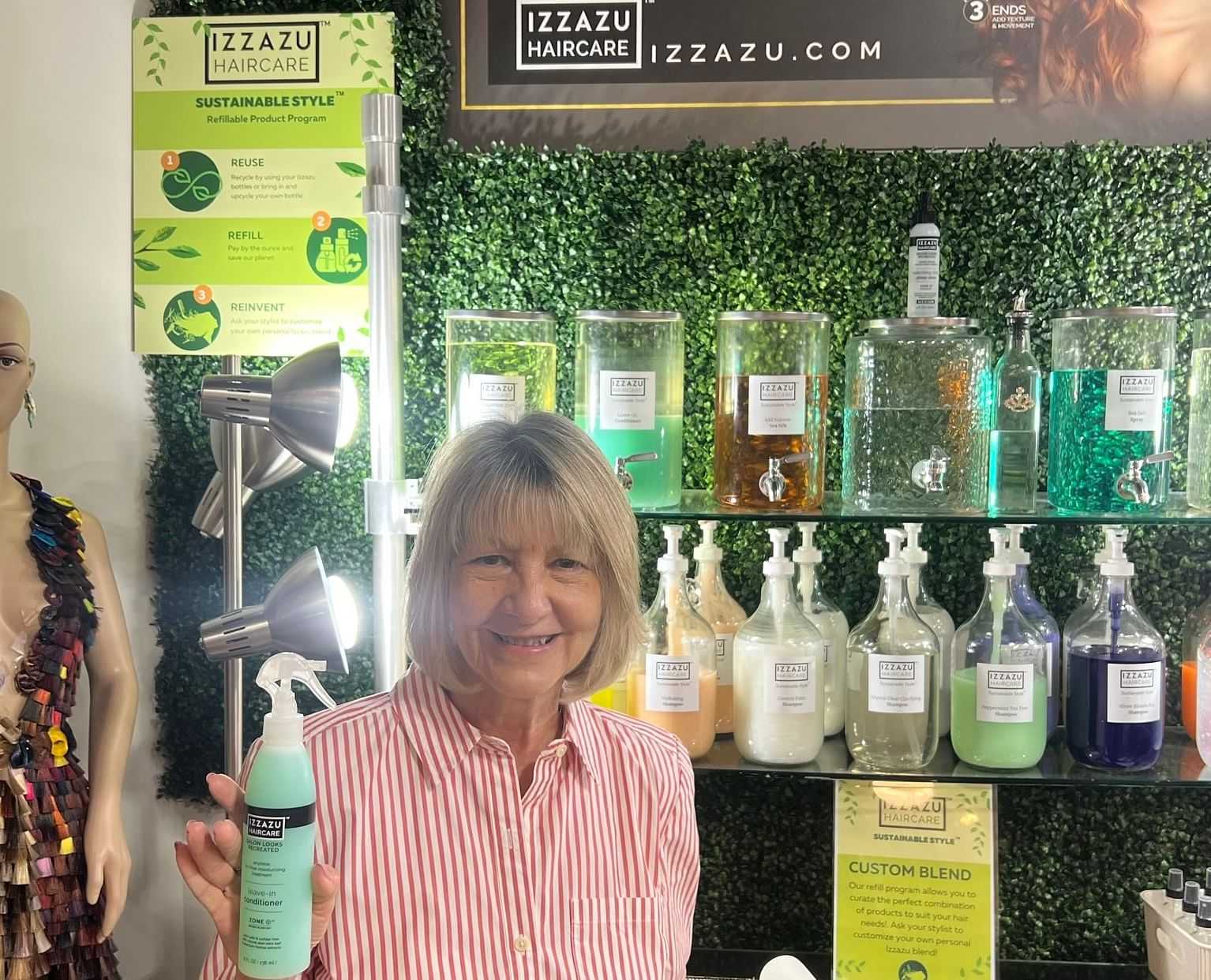 Woman holding a hair product bottle in front of a sustainable haircare display.